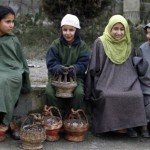 Kashmiri children warm themselves using "Kangris", or traditional fire pots, as they sit outside a polling station on a cold winter morning